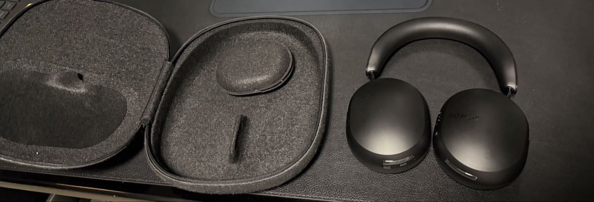 Sonos Ace headphones next to the open gray felt case